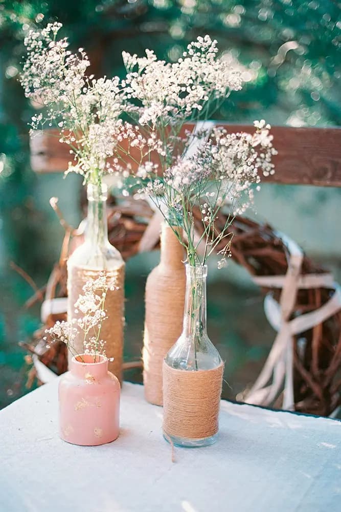 Wild flowers in twine-wrapped bottles on a sunlit table
